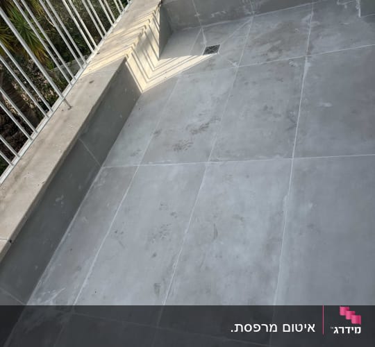 מרפסת מרוצפת באריחים אפורים לאחר עבודת איטום וגימור עם נקז מים